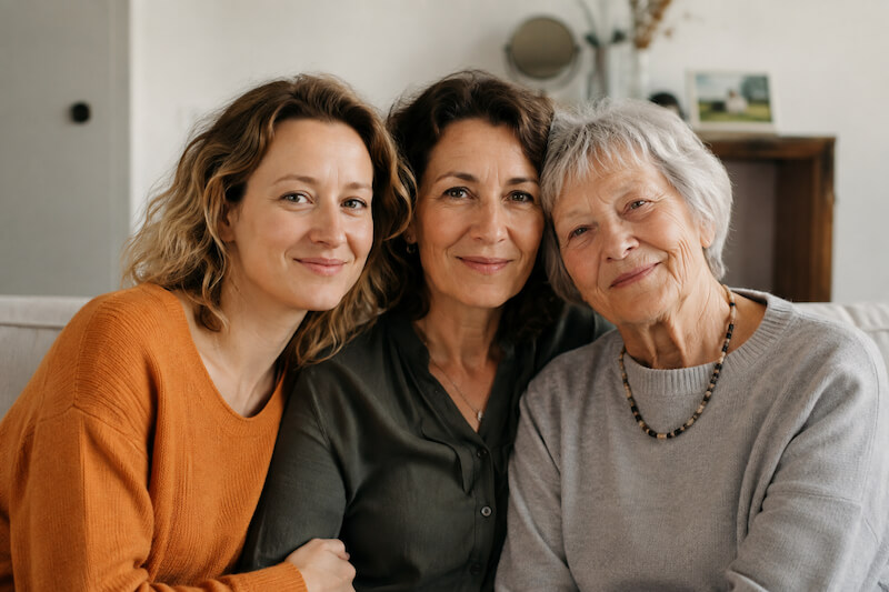 Drei Generationen einer Familie in einer warmen Begegnung – Symbol für transgenerationale Weitergabe, familiäre Verbundenheit und systemisches Verstehen.